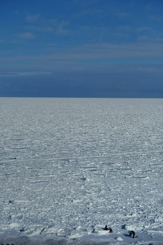 Des (petits) promeneurs face à l'immensité de l'étendue de glace de la mer d'Okhotsk