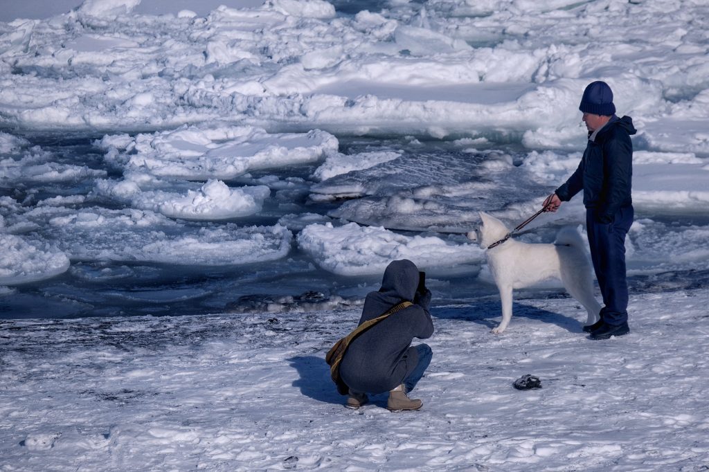 Des promeneurs profitent du soleil et de la glace dérivante le long d'une plage de la mer d'Okhotsk