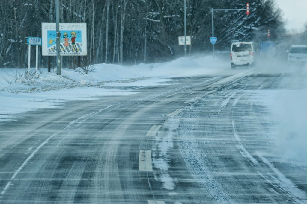 Le vent souffle la neige sur le route près d'Abashiri