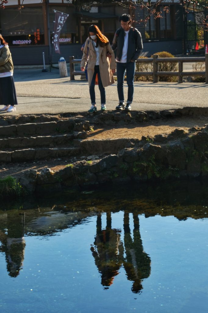 Un couple contemple les eaux magnifiques d'un étang d'Oshino Hakkai