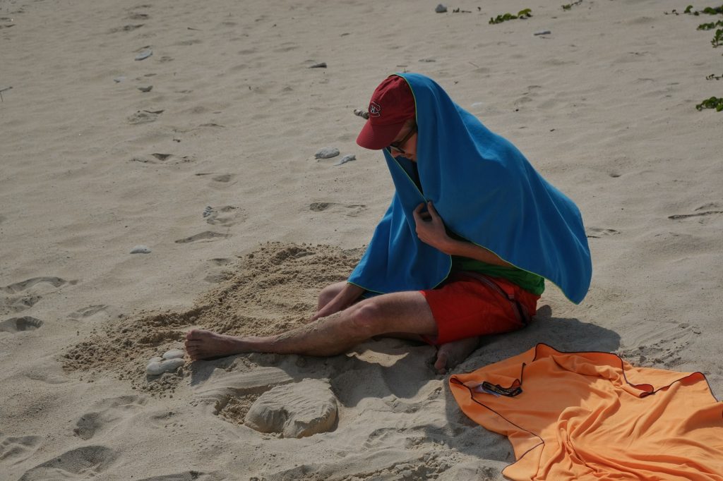 Vincent, protégé du soleil, enterre son pied sur la plage d'Aharen