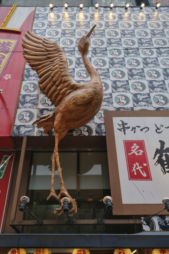 Une grue majestueuse devant un restaurant du Shinsekai
