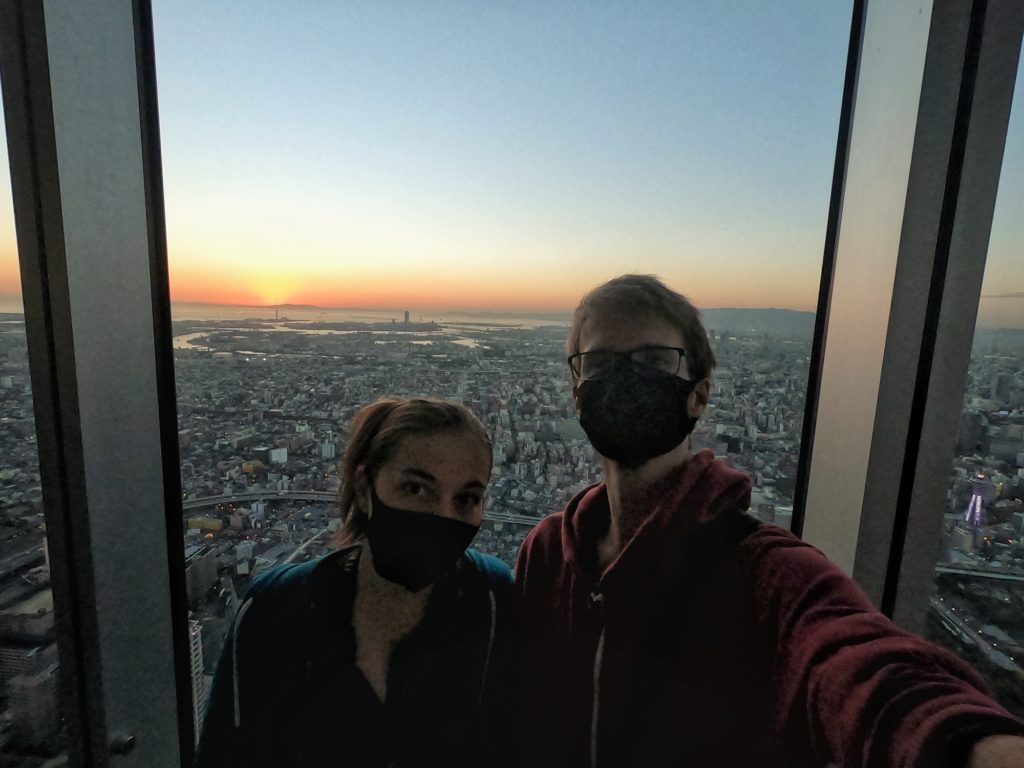 Selfie masqué devant les derniers rayons du soleil et la baie d'Osaka à l'Abenu Harukas