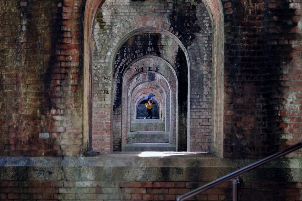 Une personne passe sous les arches de l'aqueduc de Suirokaku