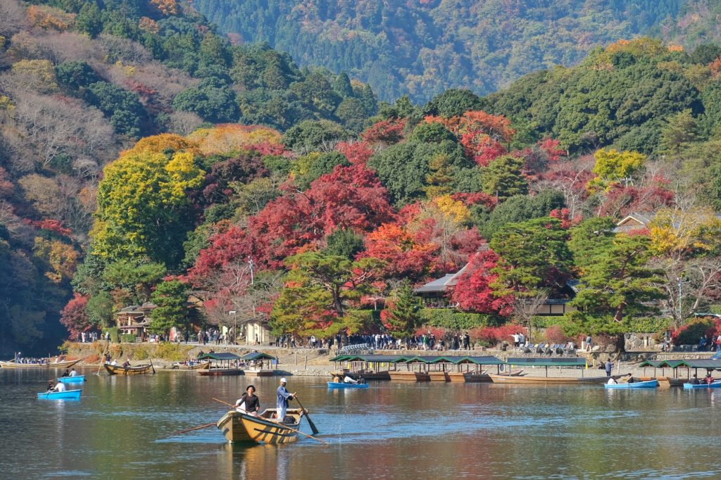 Les bateaux de la rivière Katsura devant les couleurs d'automne du parc Arashiyama