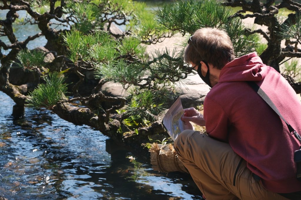 Vincent observe le ruisseau et les arbres du parc Koraku-en